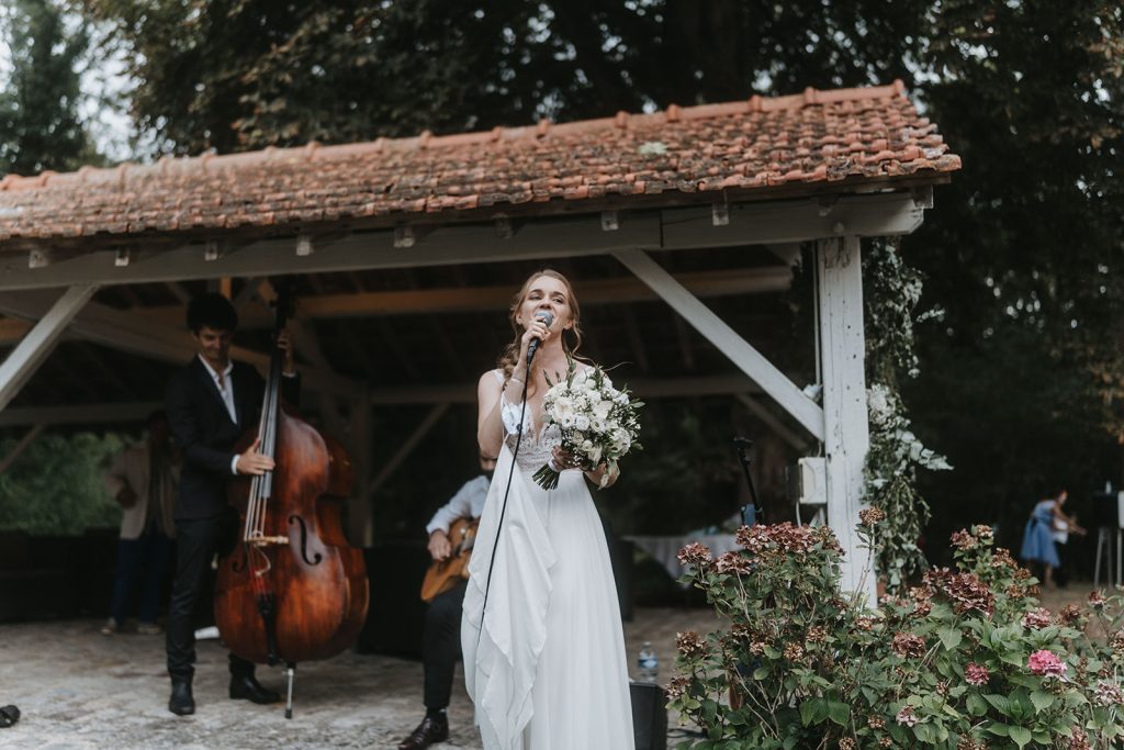 Mariée qui chante avec le groupe de musique engagé pour le cocktail de mariage